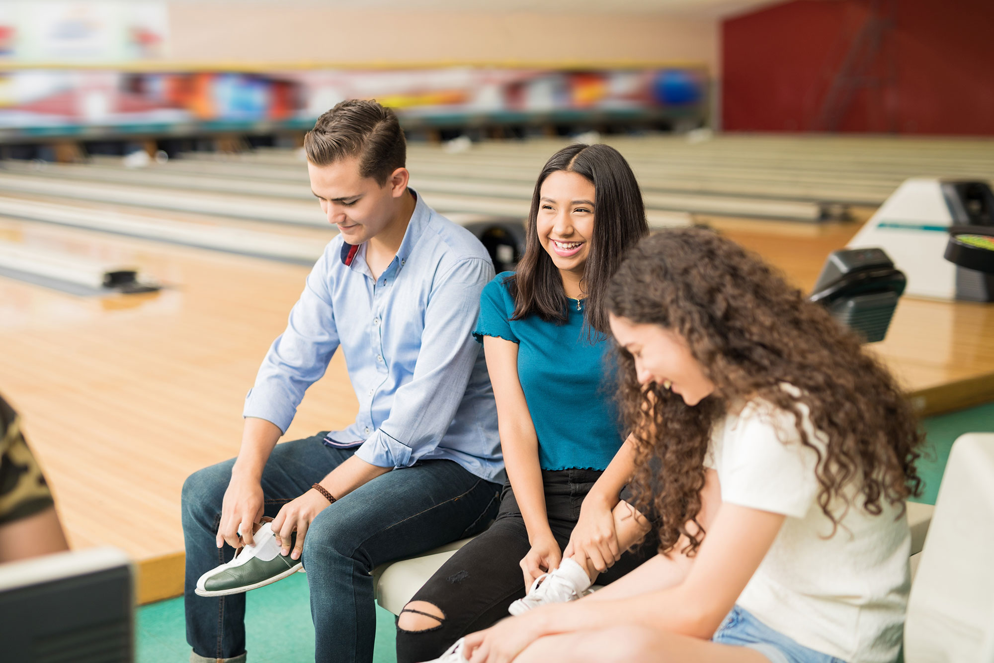 friends getting ready to bowl and putting on bowling shoes